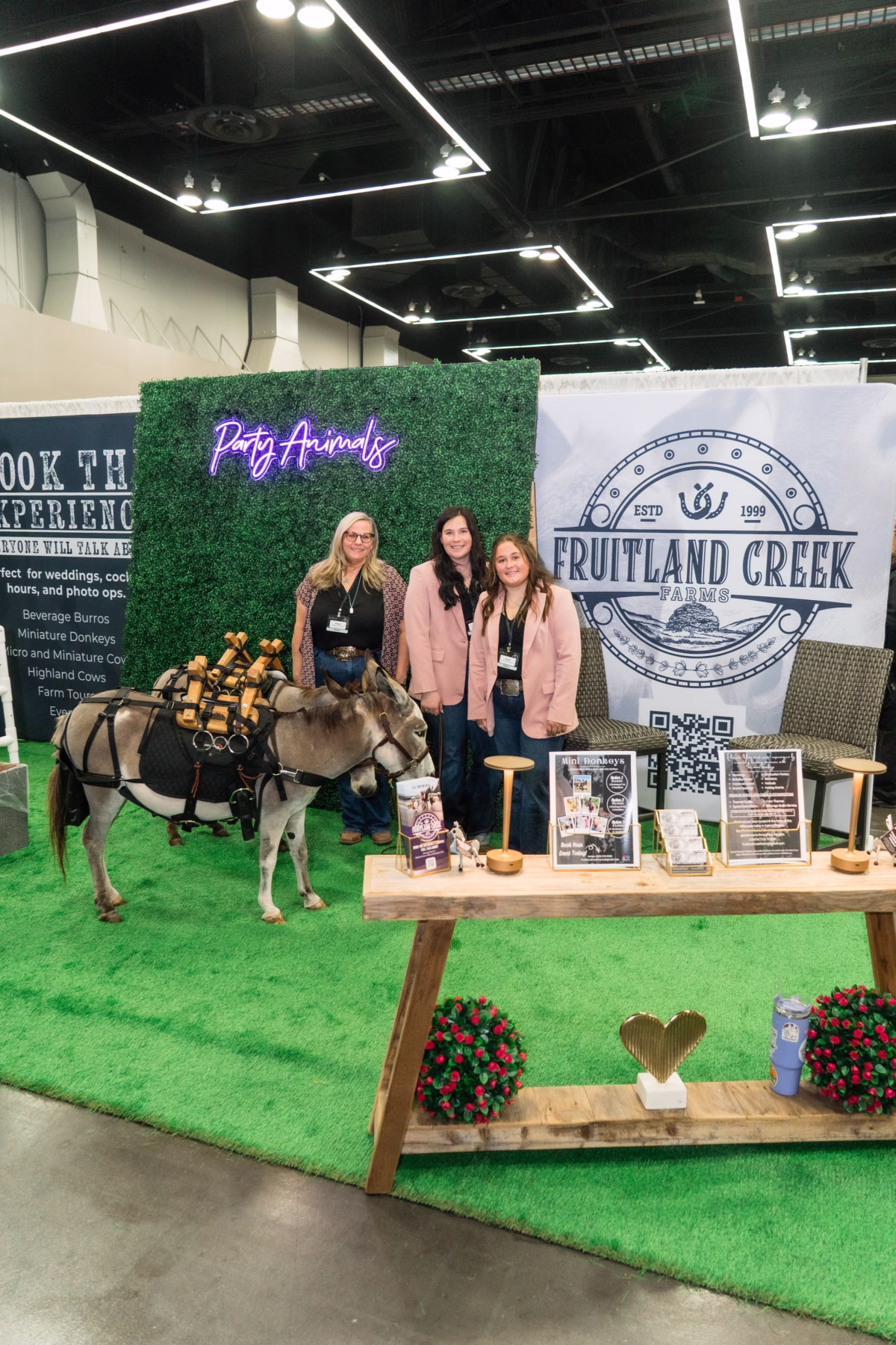 Fruitland Creek Farms wedding venue exhibit featuring petting zoo animals and three staff members at The Portland Wedding Show 2026