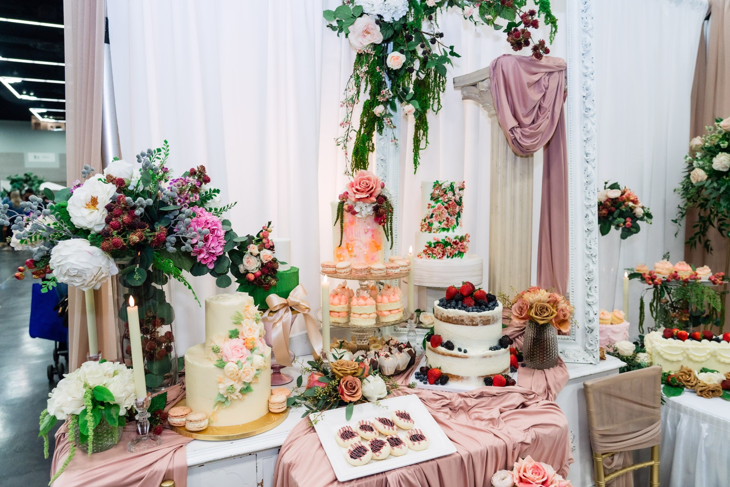 portland wedding show dessert table floral display bridal - The Portland Wedding Show Elegant wedding dessert table with tiered cakes, floral arrangements, and macarons displayed at Portland Wedding Show bridal expo