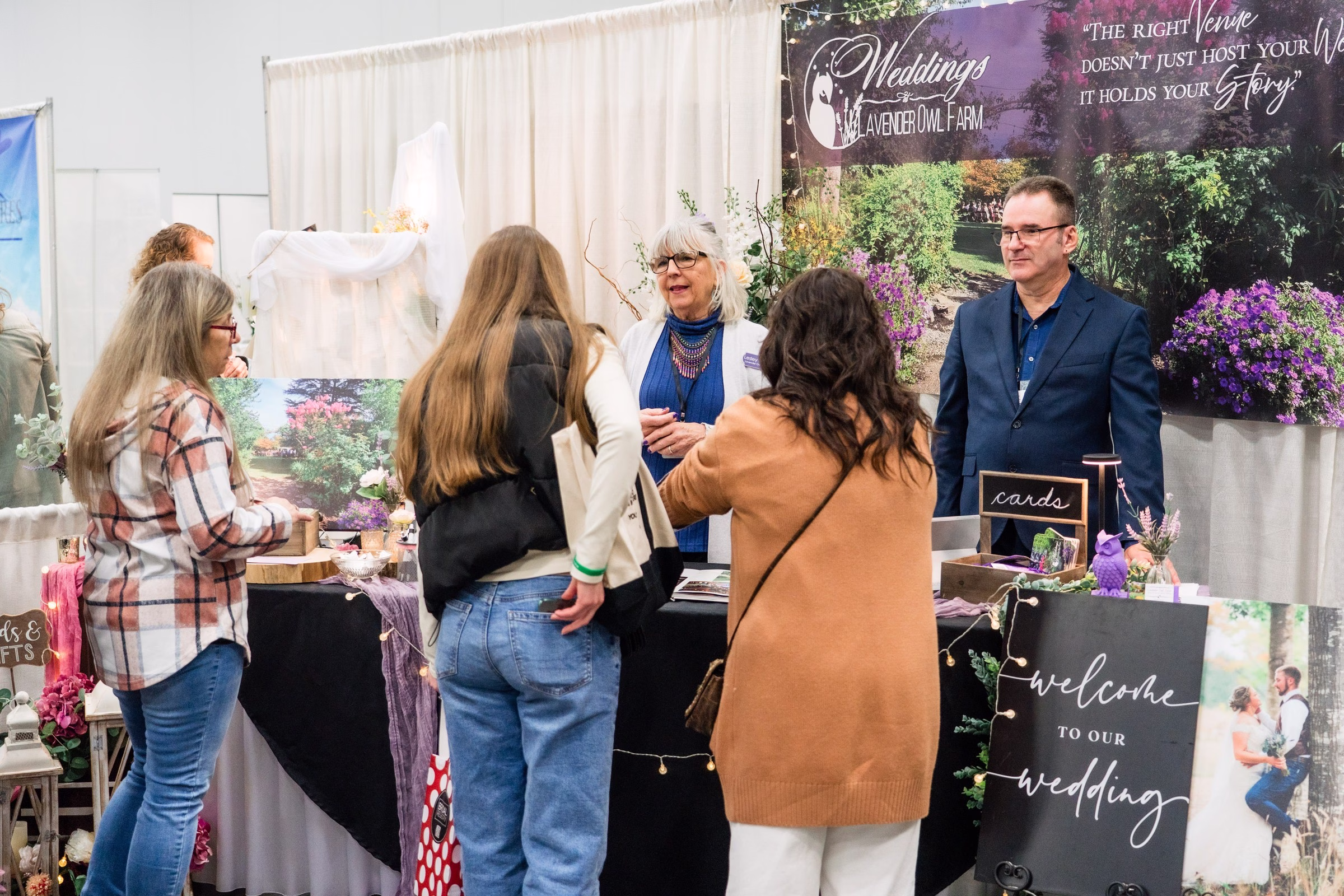 Woodland Farm wedding venue booth at Portland Wedding Show featuring lavender farm setting and venue representatives speaking with engaged couples